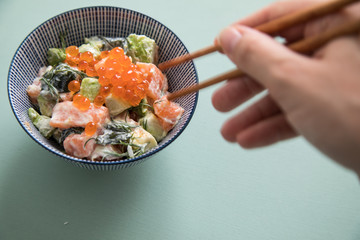 Frau isst rohes Lachs Avocado Tatar und Keta Kaviar mit Holz St&auml;bchen