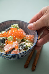 Frau serviert rohes Lachs Avocado Tatar mit Keta Kaviar und Holz Stäbchen