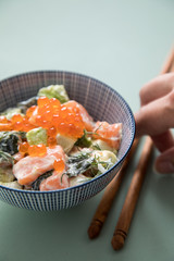 Frau isst rohes Lachs Avocado Tatar und Keta Kaviar mit Holz Stäbchen