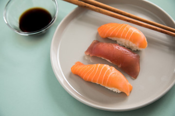 Lachs und Tunfisch Nigiri Sushi mit Sojasauce und Holz Stäbchen auf Porzellan Teller