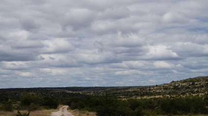 white rock road in the mountain below a cloudy sky