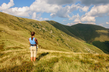 Naklejka na ściany i meble A girl with baby in a sling looks at the mountain range. Ukraine. Carpathian mountains