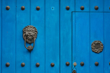 Door knocker in the form of a lion head on an old wooden door in blue color - Cartagena / Colombia
