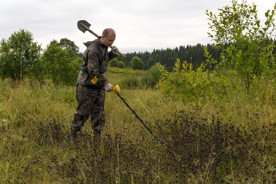 treasure hunter with a shovel and metal detector in a natural landscape