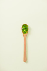 Close up of green softgel capsules with wooden spoon on isolated white background.