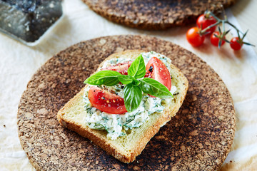 Vegetarian breakfast of champions. Sandwich with egg paste with dill on toasted bread. Tomatoes cocktail and basil on top.