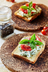 Vegetarian breakfast of champions. Sandwich with egg paste with dill on toasted bread. Tomatoes cocktail and basil on top.