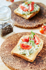 Vegetarian breakfast of champions. Sandwich with egg paste with dill on toasted bread. Tomatoes cocktail and freshly picked twig of young thyme on top.