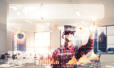 Young man in modern office interior experiencing virtual reality