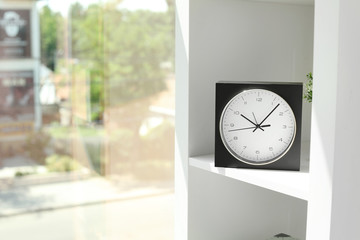 Analog clock on shelf indoors. Time of day