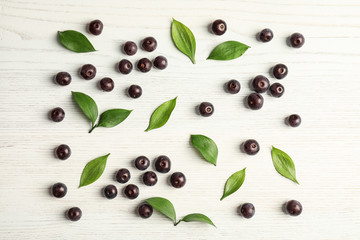Flat lay composition with fresh acai berries and leaves on wooden background