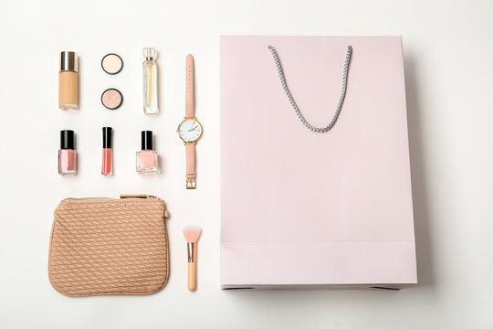Flat lay composition with shopping bag and cosmetics on white background