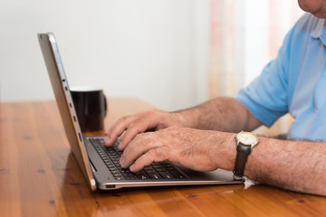Close up senior man hands working on laptop
