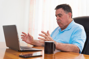 Fototapeta premium Angry senior man working on laptop. Negative emotion.