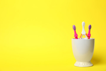 Baby toothbrushes in holder and space for text on color background