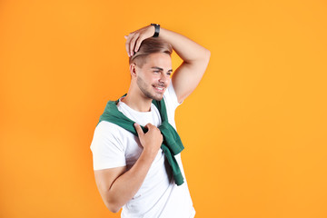 Young man with trendy hairstyle on color background