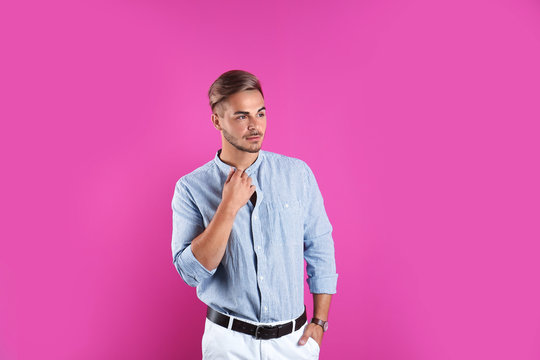 Young man with trendy hairstyle on color background