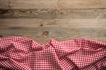Red white checkered picnic tablecloth on wooden background, copy space