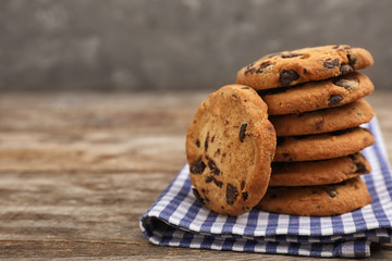 Stack of cookies with chocolate chips on wooden table, space for text