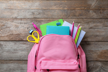 Flat lay composition with backpack and school stationery on wooden background