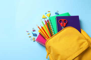 Flat lay composition with backpack, school stationery and space for text on color background
