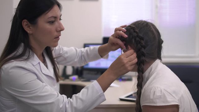 Doctor helps a girl with a hearing aid