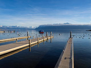 Winter lake in sunny day with blue sky, boats and birds. Geneva lake or Lac Leman in late summer and beginning of autumn in Lausanne, Switzerland