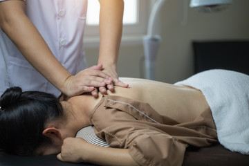 Physiotherapist giving back massage to a woman in clinic