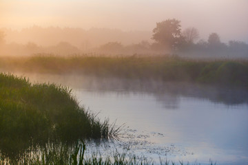 River curve covered in thick fog in countryside