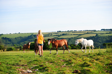 Young woman in a field with horses in landscape