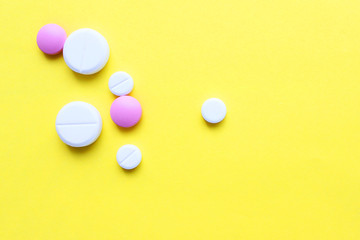 a lot of colorful pills of different shapes on a yellow background. 