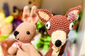Various knitted animals toys on a shelf at home or for sale at baby shop