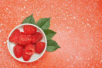Fresh red raspberry on color background with green leaves. Ingredients for cooking. Top view.