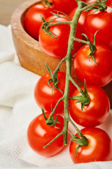 Fresh Red Cherry tomatoes in bowl on wooden background with textile napkin. Ingredients for cooking. 
