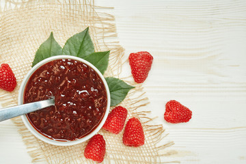 Raspberries jam with fresh red ripe on wooden background with napkin. Top view.