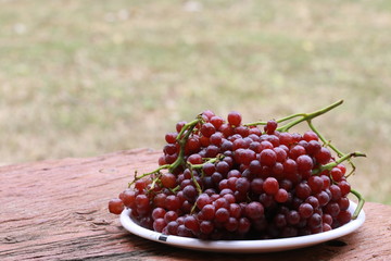 Red  grape fruits in glass cup and white bokeh on green background