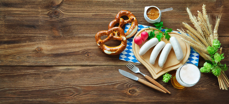 Bavarian sausages with pretzels, sweet mustard and beer on rustic wooden table