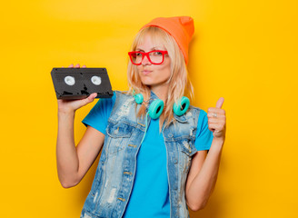 portrait of young adult girl orange hat with VHS on yellow background