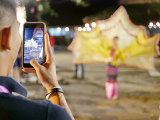 Close up of tourist's hands lifting his phone up to take a photo of beautiful traditional Northern...