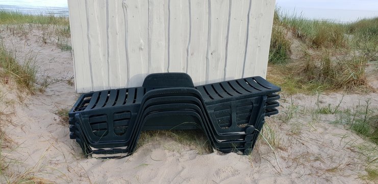 Stacked sun beds laying in the Baltic sea beach near changing room.