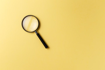 Magnifying glass on yellow background. Top view. Flat lay. Copy space. Concept