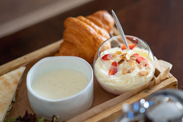 Breakfast table with oatmeal porridge, croissants, fresh fruit and muffins overhead shot