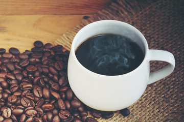White cup of coffee with coffee bean on sackcloth background