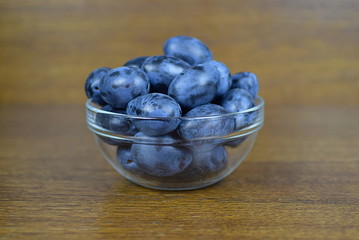 fresh plums in a glass bowl on a wooden table