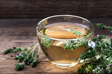Herbal tea with thyme over rustic wooden background.