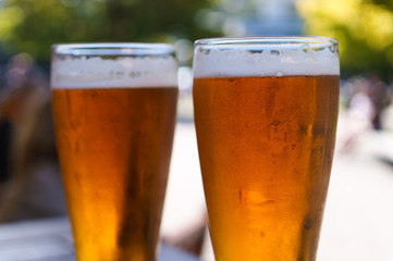 Two full glass of beer with condensation and foam