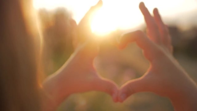 Girl doing heart hands against the sky, child hands forming a heart shape with sunset silhouette, love, dream, summer