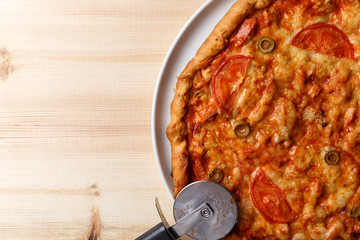 Homemade pizza and a pizza cutter on wooden table. Top view. Flat lay. Copy space. Close up