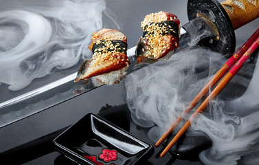 Close up of sushi set with chopsticks .Sashimi.Nigiri. On katana sword with fog .Creative shot. Japanese athmophere.