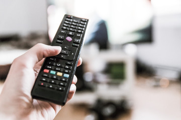 Fernbedienung vor Fernseher in Männerhand 